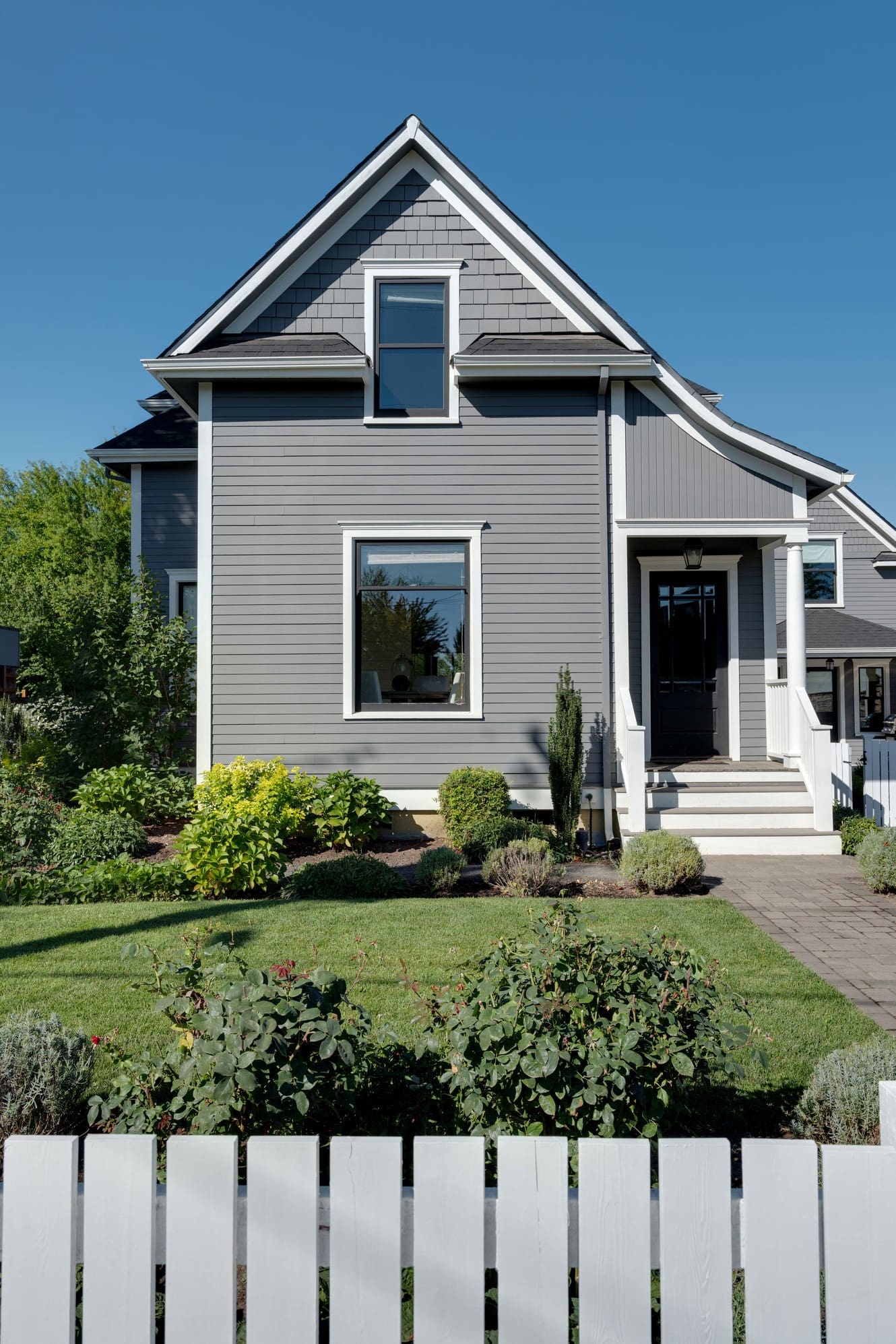 Gray house with garden and white fence.
